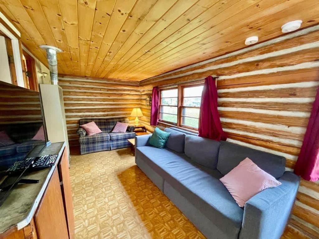 una sala de estar con un sofá azul en una cabaña de madera en 1-Bedroom Balsam Lake Cottage #9, en Kawartha Lakes