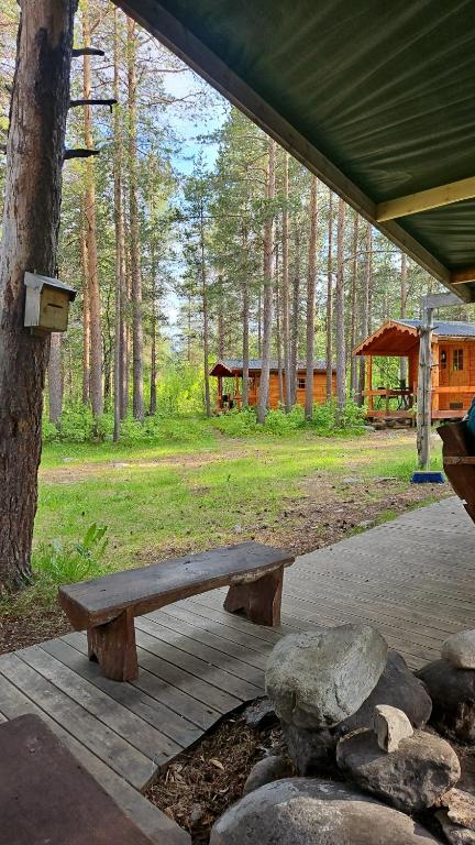 a wooden bench sitting under a tent in a forest at Tørfoss Gård, Hytte utleie, Campingvogn og bobil plasser in Potka