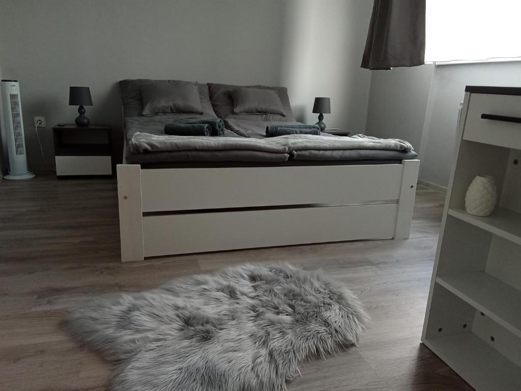 a bedroom with a bed with a furry rug on the floor at Jucus Apartman in Makó