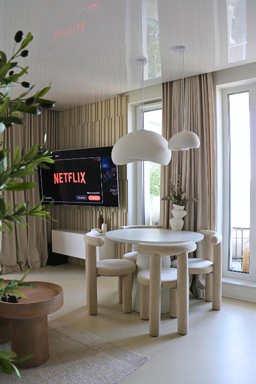 jadalnia ze stołem, krzesłami i telewizorem w obiekcie Centaurus Olsztyn Sunset Apartament - Dwa Balkony & Darmowy Parking podziemny & Stare Miasto & Galeria & Widok & Planetarium & Centrum miasta w Olsztynie
