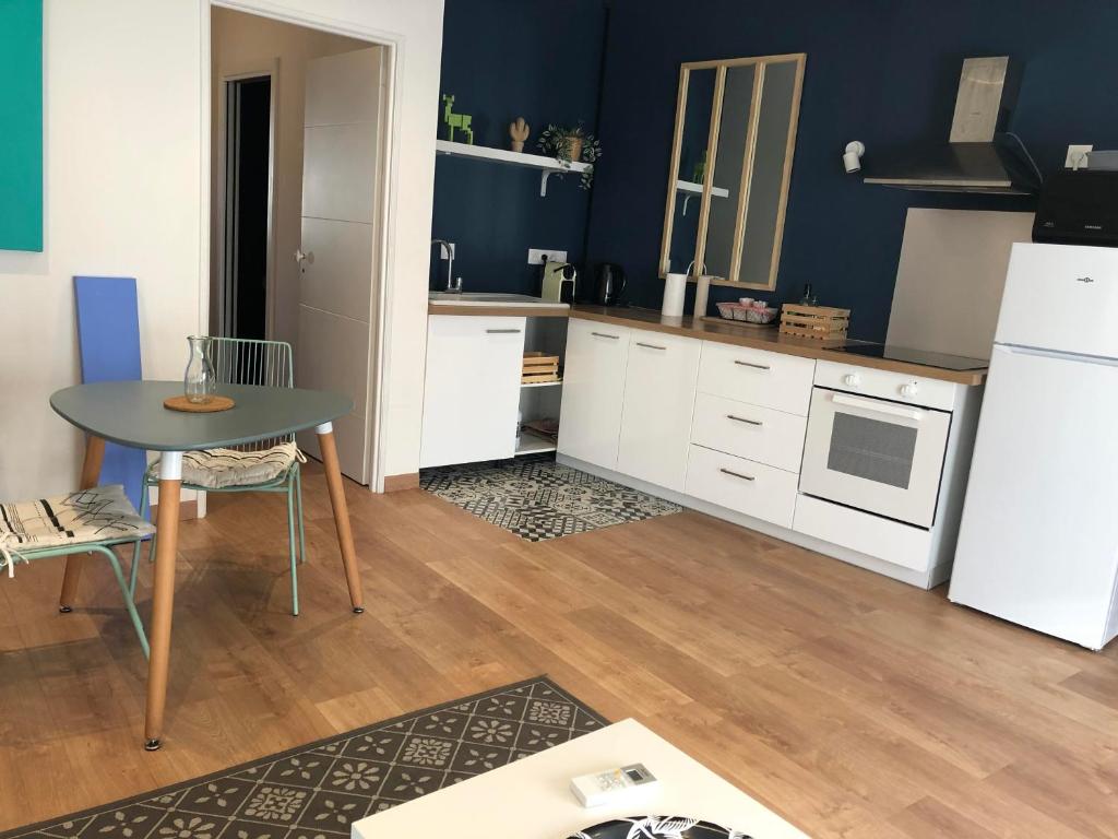 Una cocina con una mesa y un refrigerador blanco. en Nomad's house - 2G, en Aviñón