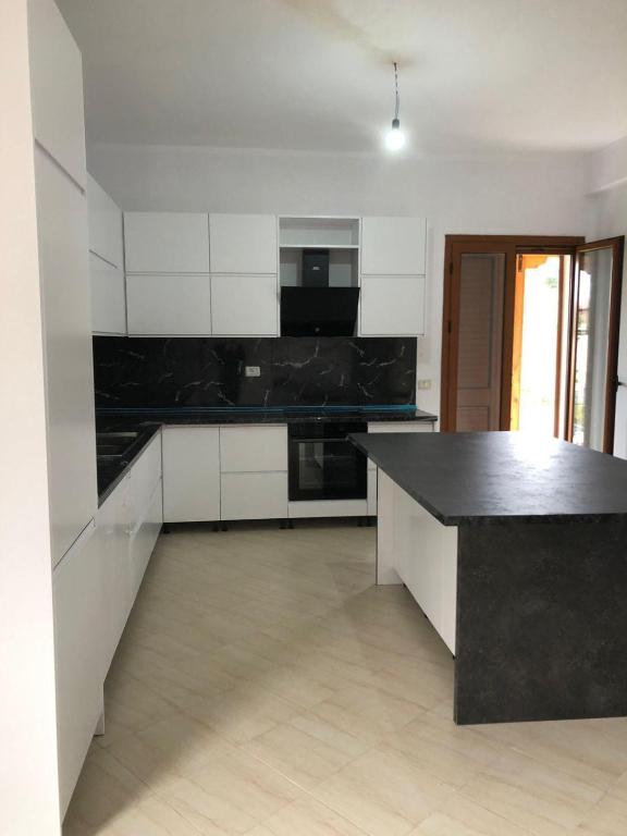 a kitchen with white cabinets and a black counter top at Vila Mehalla in Arape-Rashbulli