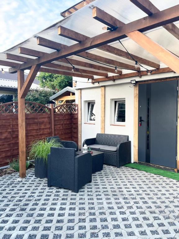 a patio with a wooden pergola and couches at Domki Letniskowe Ster in Międzyzdroje