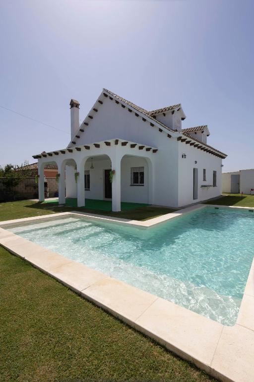 a villa with a swimming pool in front of a house at Montijo Relax and Sunny Private Pool in Cádiz