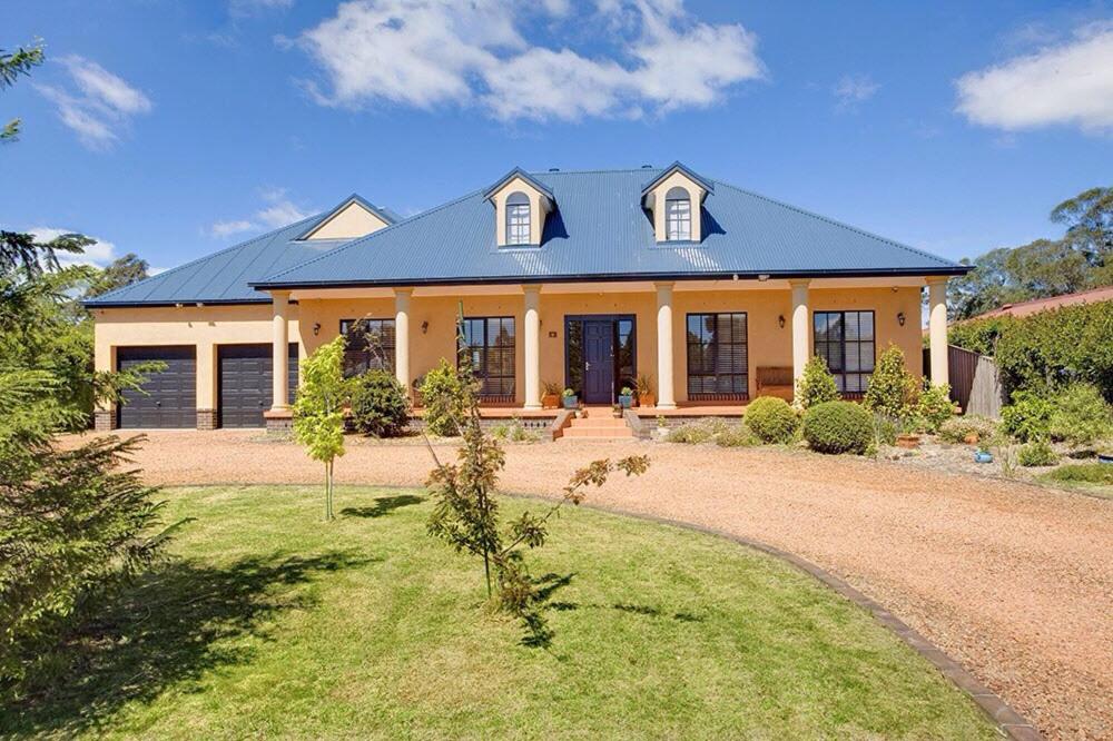 a house with a blue roof and a yard at Stately Bowral Designer Home in Bowral
