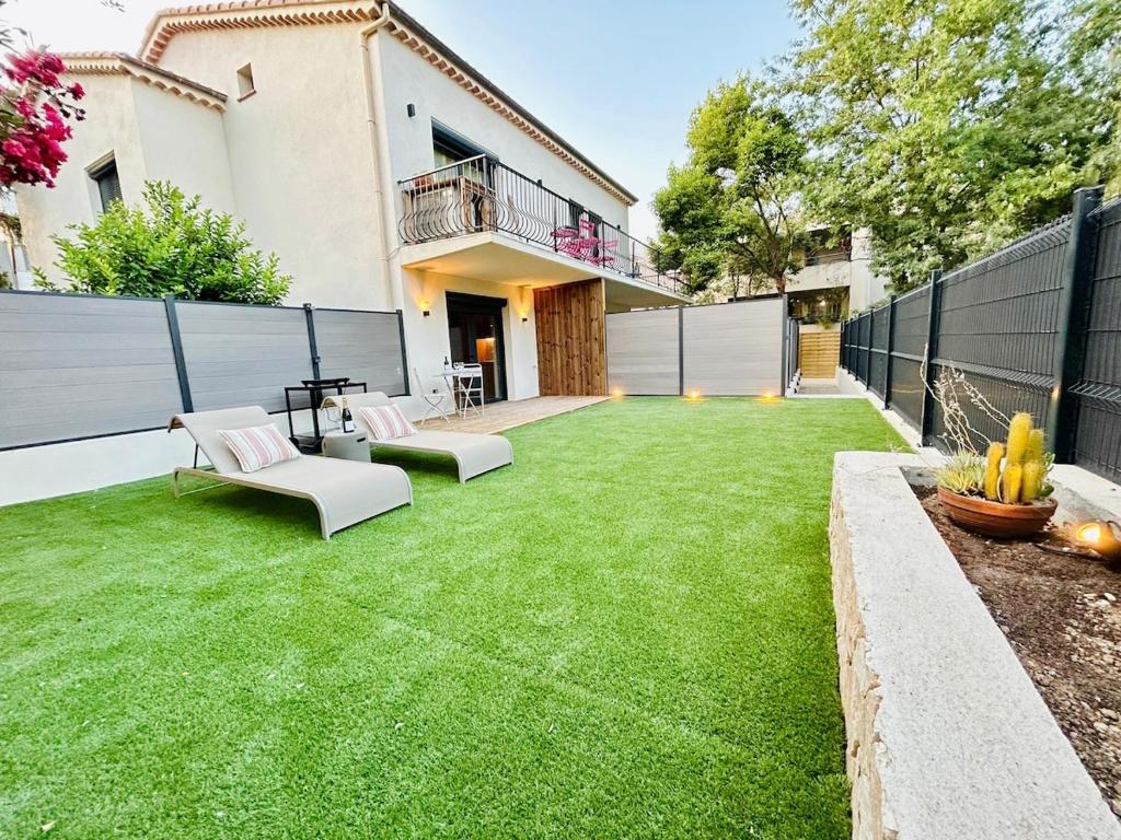 un patio trasero con césped verde y una valla en Stylish Garden Escape- BBQ, Projector & Exclusive Parking, en Cagnes-sur-Mer