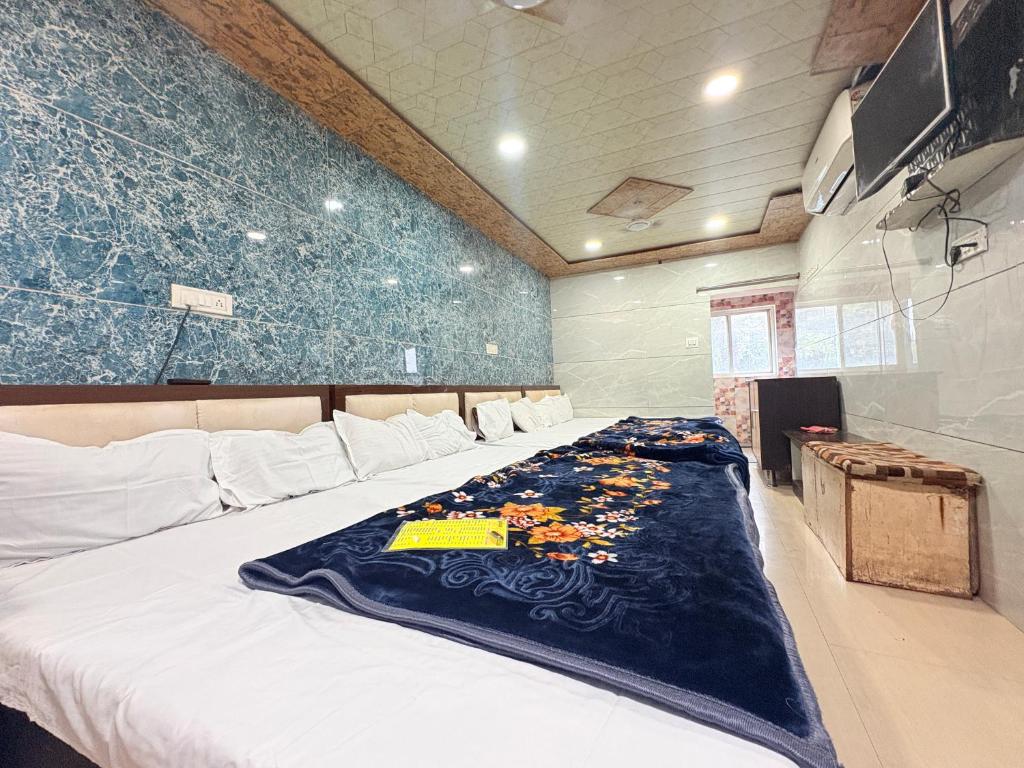 a bedroom with a bed with a blue blanket on it at Hotel Shree dhan Laxmi palace in Jāmb
