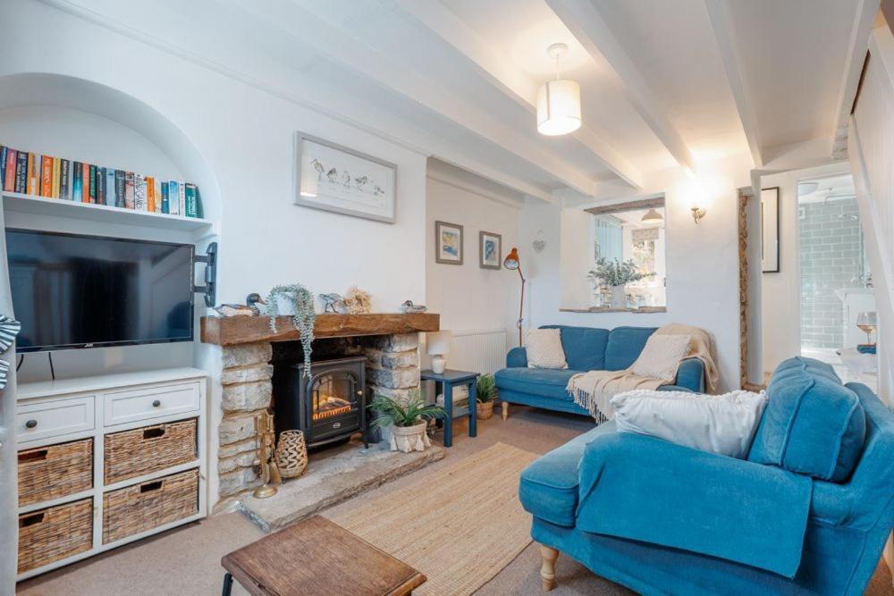 a living room with blue furniture and a fireplace at Angel Cottage in Swanage