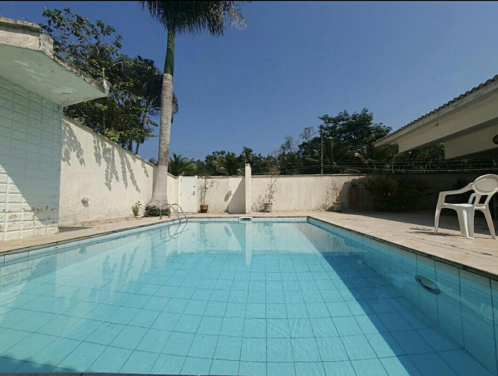 a swimming pool with a palm tree and a chair at casa com piscina da edi fontes in Guarujá