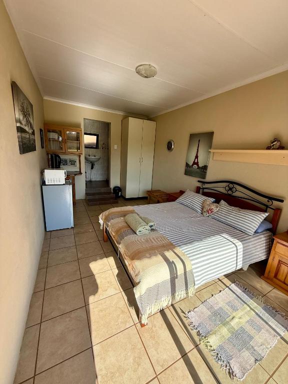 a bedroom with a large bed and a kitchen at La Ronel Guest Farm in Roossenekal