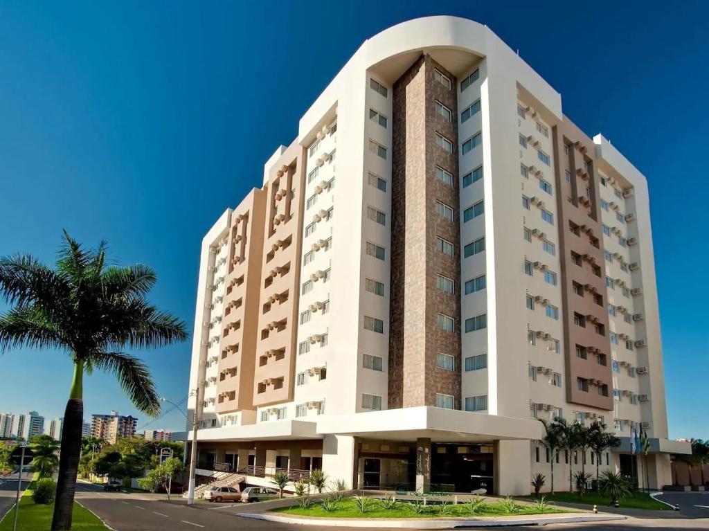 un grand bâtiment avec un palmier devant lui dans l'établissement Le Jardin - Via Caldas, à Caldas Novas