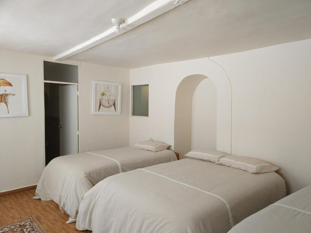 two beds in a room with white walls at Centro Cusco Inti Saphy in Cusco