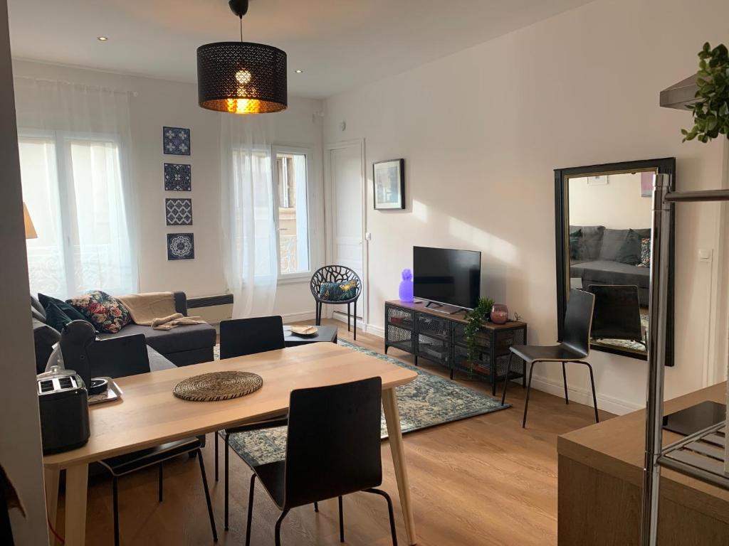 a living room with a table and a couch at Le Quatre superbe T2 Internet WiFi Coeur historique Parking 45 m2 in Béziers