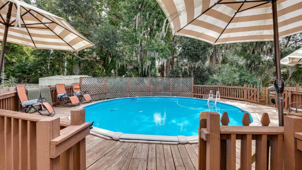 a pool on a wooden deck with umbrellas at Year-Round Pool & Backyard Near Tybee Island in Savannah