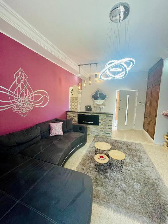 a living room with a black couch and a pink wall at Dar Misk Elil in Bizerte