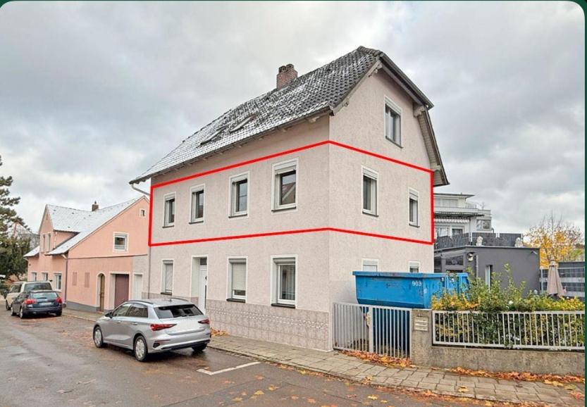a white house with a car parked in a parking lot at Neumarkt City Monteurwohnung in Neumarkt in der Oberpfalz