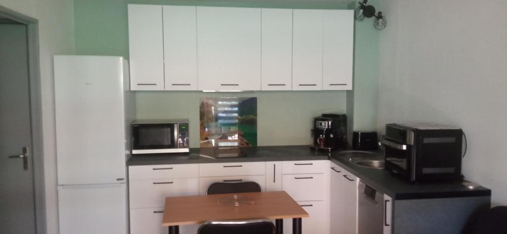 a kitchen with white cabinets and a sink and a microwave at la brise marine in Plage dʼArgelès