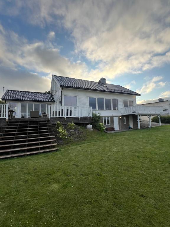 a white house with stairs and a grass yard at Hybel leilighet på Rosanes, Teie in Lii