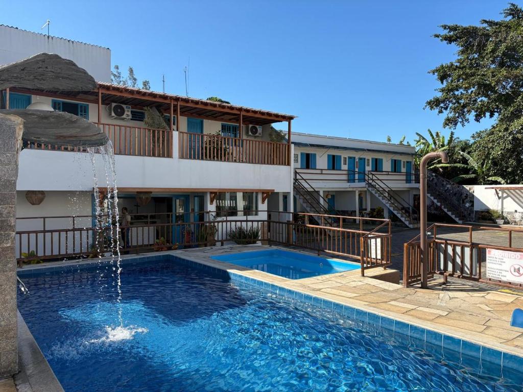 a swimming pool with a fountain in front of a building at Pousada Mar E Mata in Guarapari
