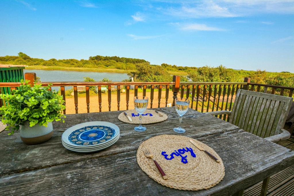 a wooden table with hats and wine glasses on it at beautiful eco-beach house next to bird reserve in Snettisham