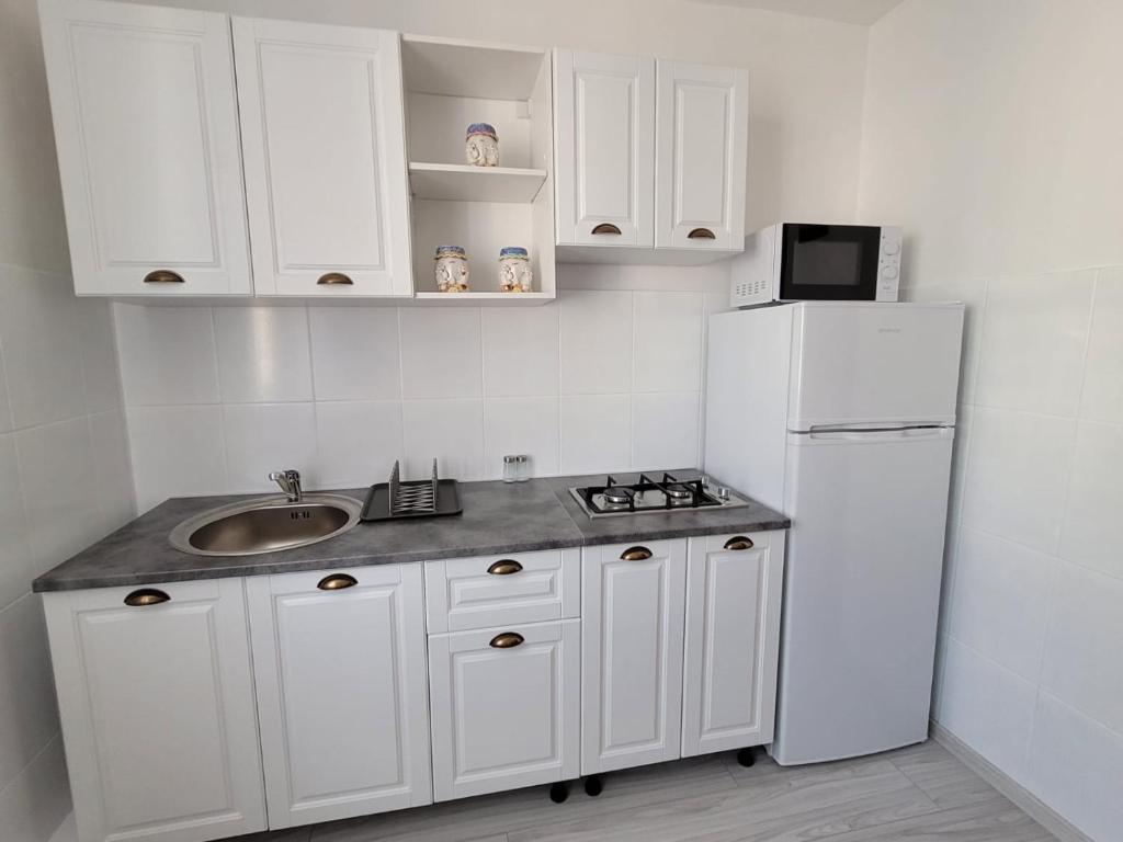 a white kitchen with a sink and a refrigerator at Central Residence in Piatra Neamţ