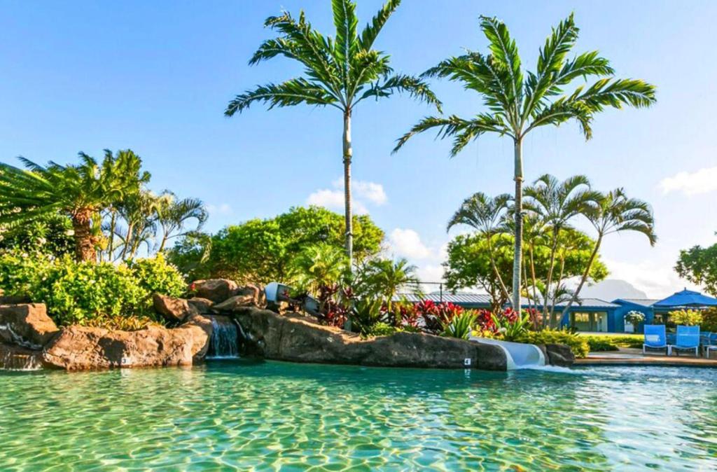 a pool at a resort with palm trees and a waterfall at Regency 311 in Kipu