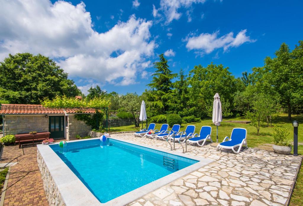 a swimming pool with chairs and a house at Villa Teodora, an ideal holiday hideaway for families and friends in Krapan