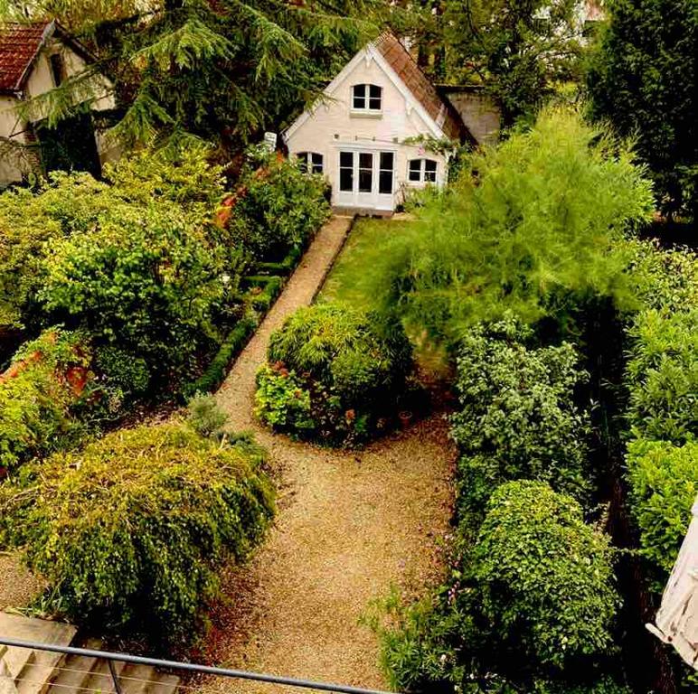 un giardino con una casa bianca e alcuni cespugli di Tiny house au fond du jardin a Chalons en Champagne