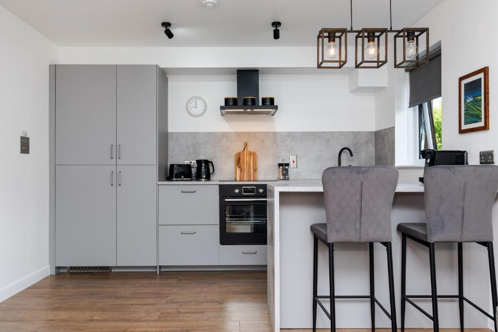 a kitchen with white cabinets and bar stools at 2Bedroom Apartment-Free Parking in Edinburgh