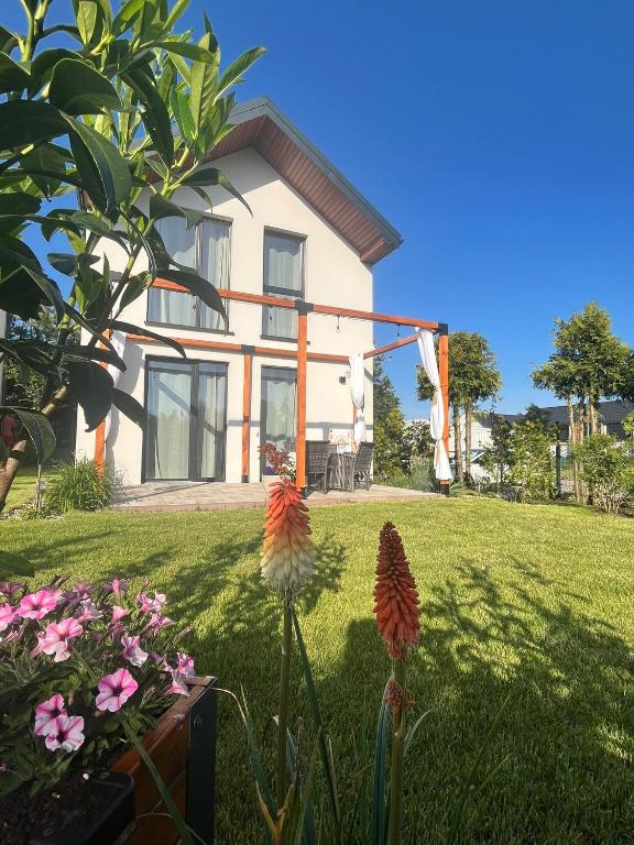 a house with some flowers in front of it at Chillera Domki in Łeba