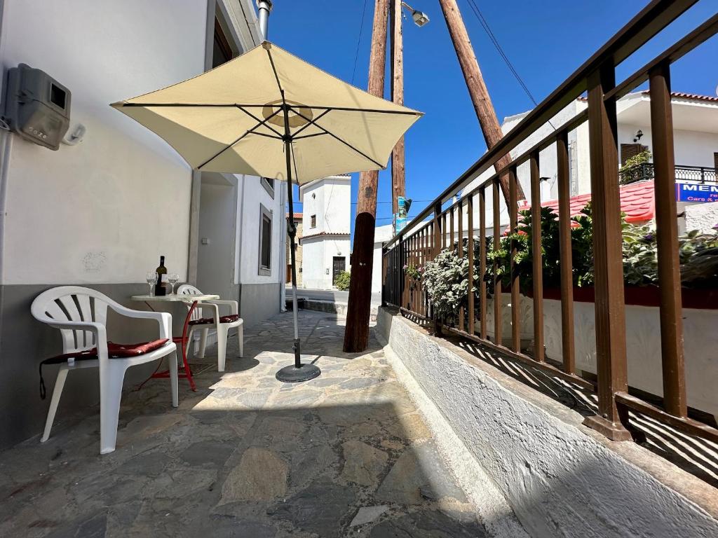 patio con mesa y sombrilla en el balcón en Ouranias house, en Kokkari