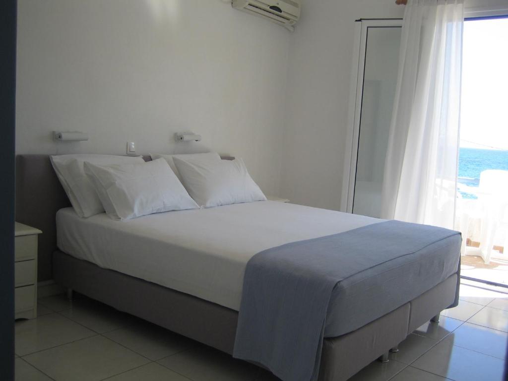 a bedroom with a white bed with a large window at Seaside Studios in Megalochori