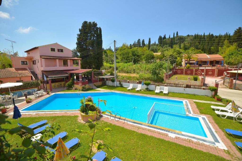 einen Pool in einem Garten mit Stühlen und einem Haus in der Unterkunft Alex Katerina Apartments in Peroulades