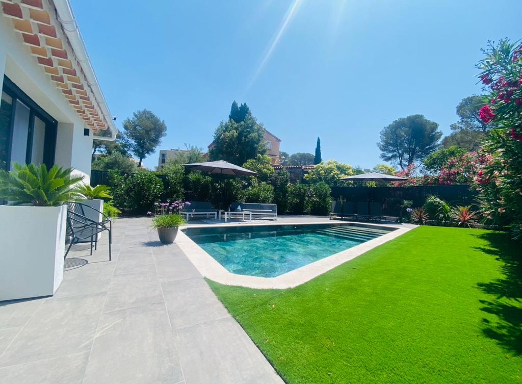 une cour avec une piscine et de l'herbe verte dans l'établissement Villa contemporaine, 5 voyageurs avec piscine, jardin et proche du bord de mer, à Saint-Raphaël