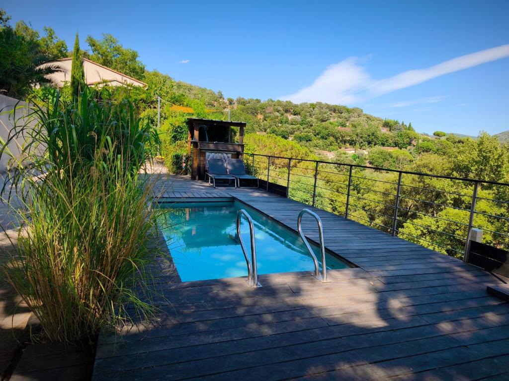 une piscine sur une terrasse en bois avec une colline en arrière-plan dans l'établissement Maison Darshan piscine 11 personnes, à Collobrières