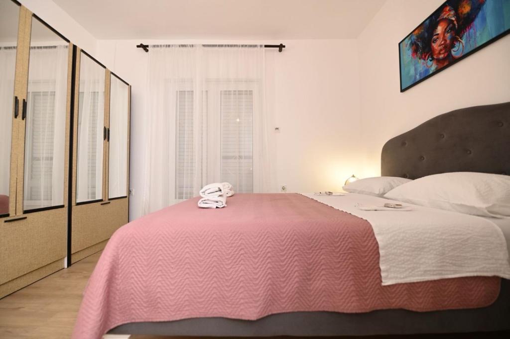 ein Schlafzimmer mit einem Bett mit einer rosa Decke in der Unterkunft Apartmani Santa Barbara in Trebinje