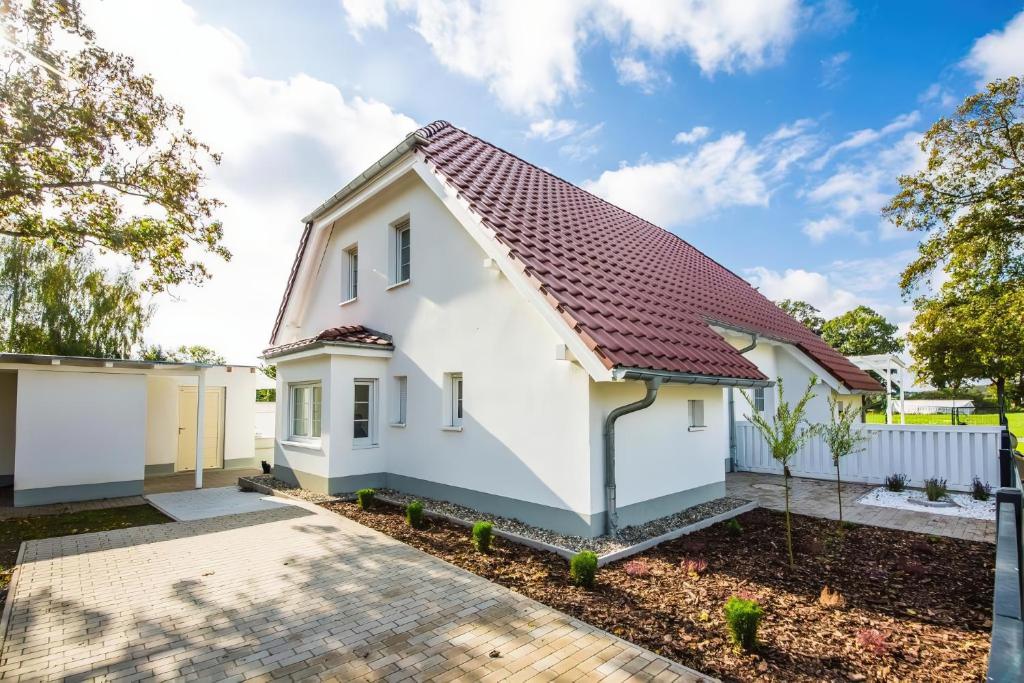 a white house with a red roof at Ferienhaus Ariane - Achterwasser-Findling in Netzelkow