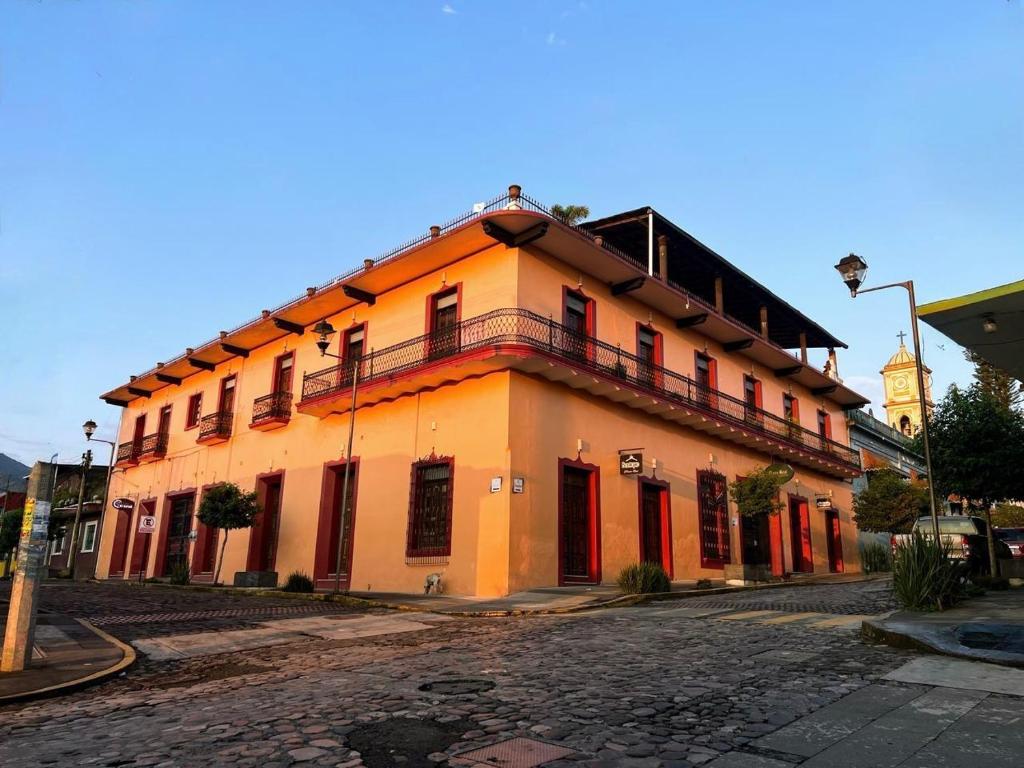 een oranje gebouw aan een straat met een klokkentoren bij Plaza Real Hotel Boutique in Coscomatepec de Bravo