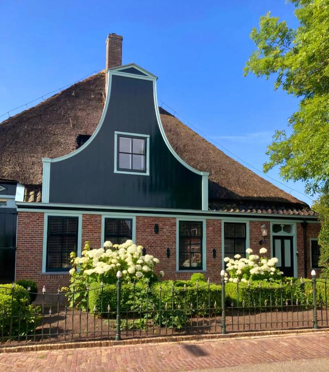 a house with a black roof and white flowers at Boerderij Blok in Barsingerhorn