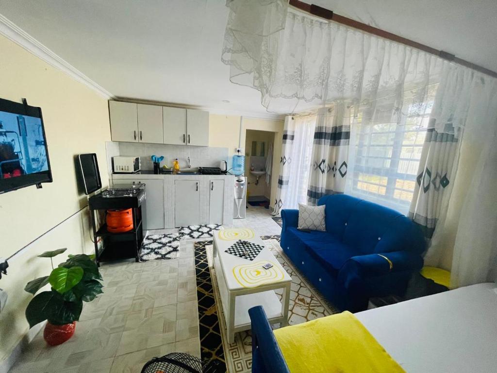 a living room with a blue couch and a kitchen at Tausi Studio Greenspot in Ruiru