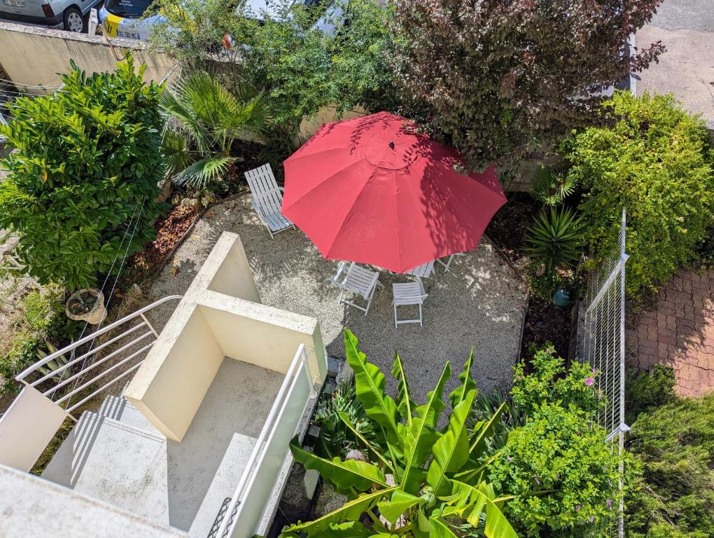 une vue aérienne d'un parapluie rouge et de chaises avec une table dans l'établissement Xanadu - Maison Design 80, à Rochefort