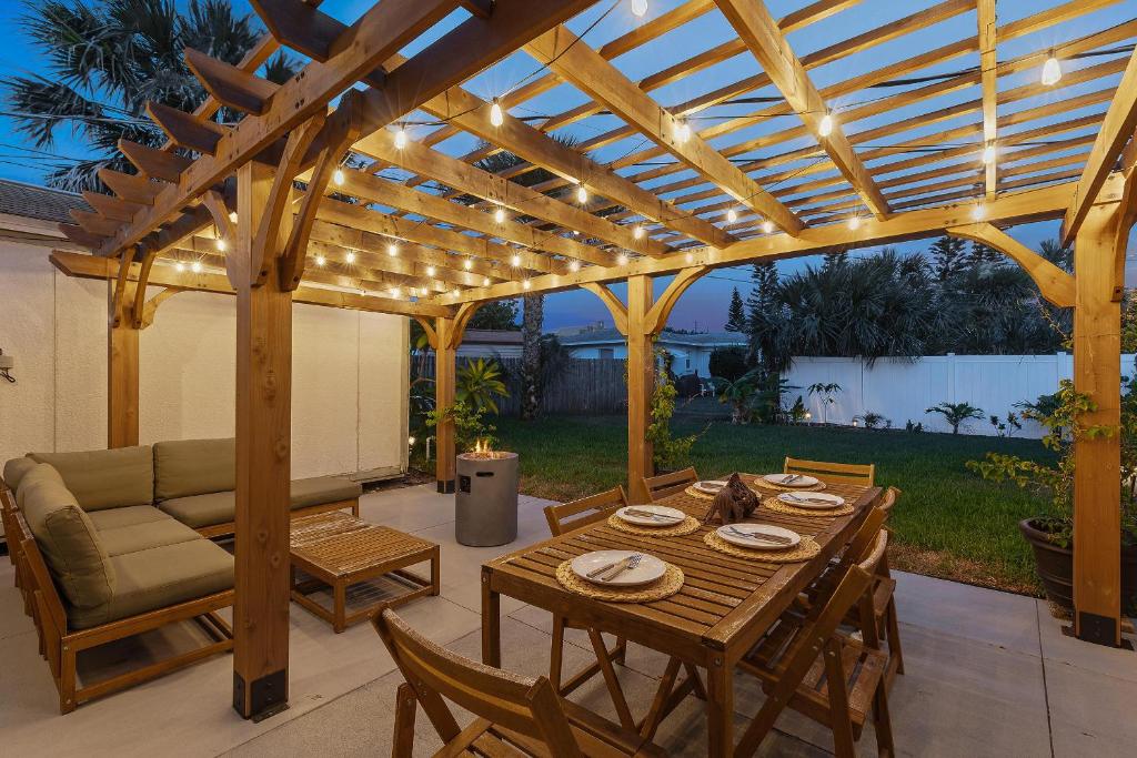 a patio with a wooden pergola with a table and chairs at Smyrna Sol in New Smyrna Beach