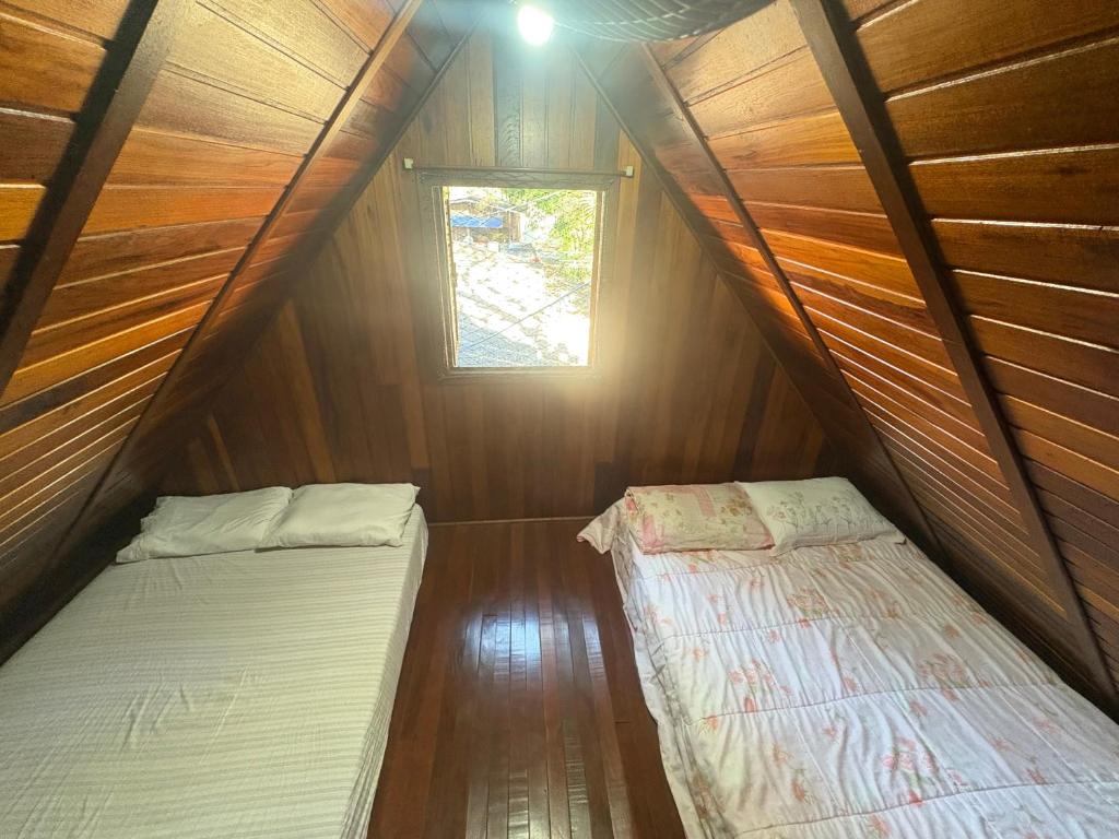 two beds in a small room with a window at Chalé em camping in Itu