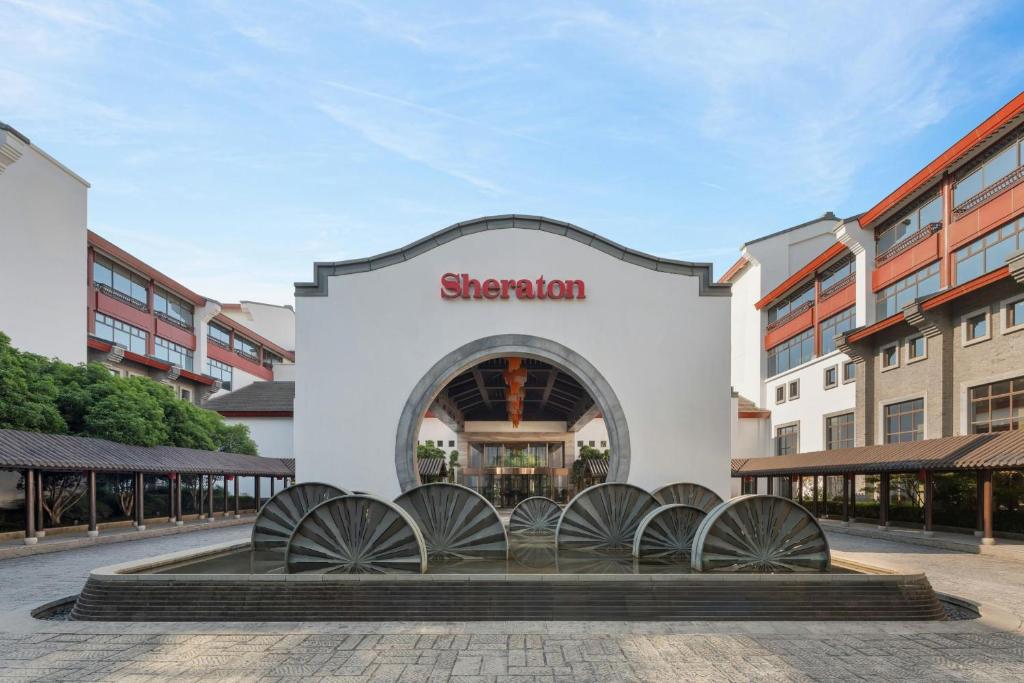a building with a group of waterwheels in front of a store at Sheraton Grand Hangzhou Wetland Park Resort in Hangzhou