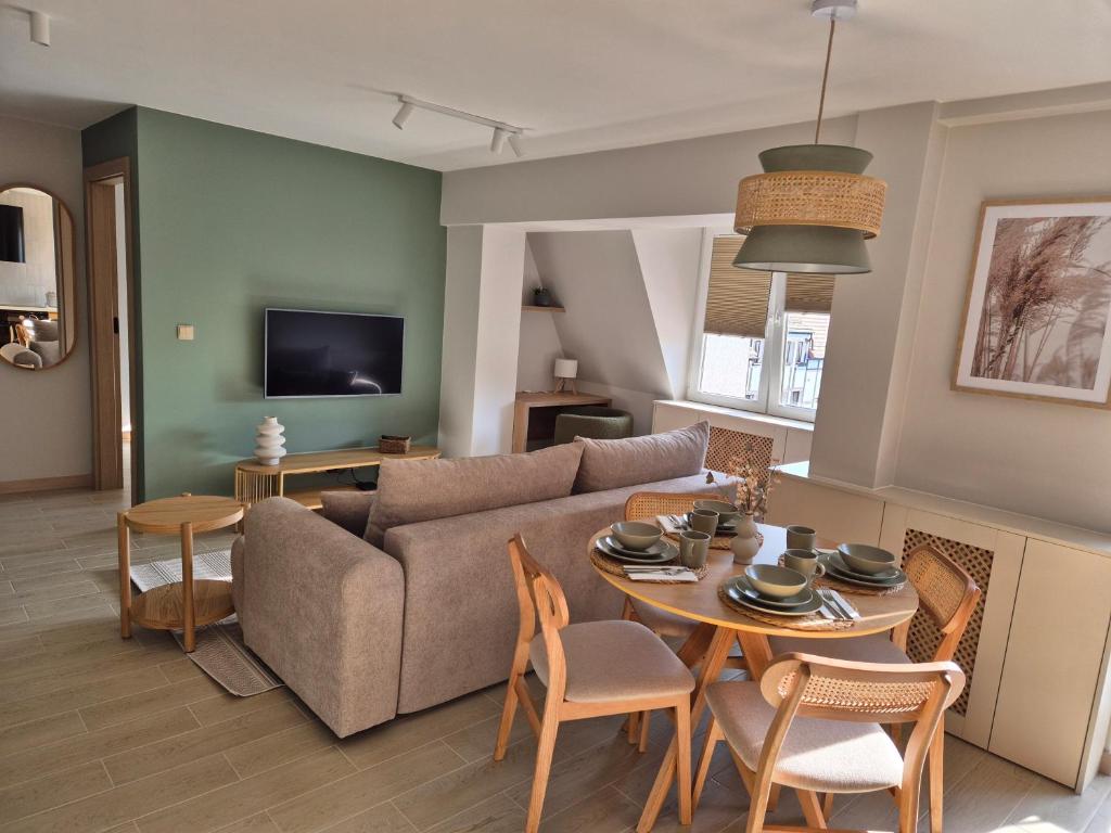 ein Wohnzimmer mit Sofa, Tisch und Stühlen in der Unterkunft Apartament Morska Harmonia in Ustka