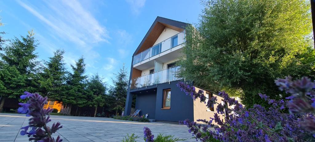 un bâtiment avec des fleurs violettes devant lui dans l'établissement NA FALI Pokoje i Apartamenty, à Wicie