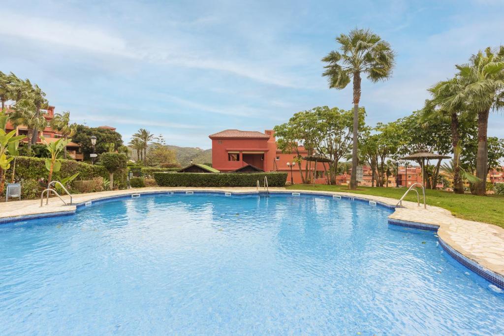 マルベーリャにあるStylish 2-Bed Apartment with Large Terrace & Poolのヤシの木が茂る庭の大きなスイミングプール