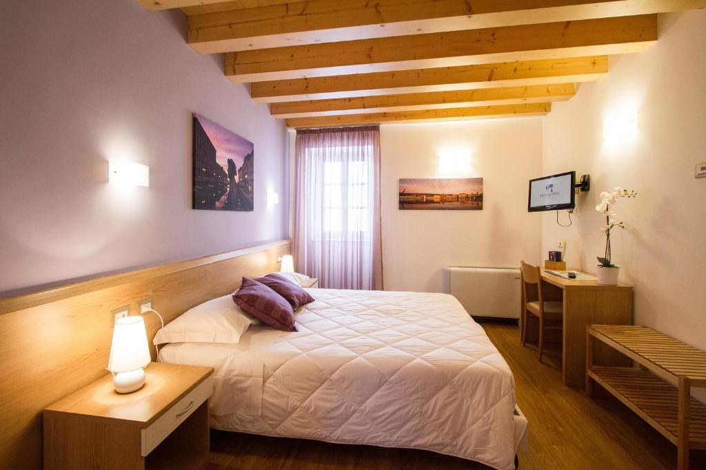 a bedroom with a bed and a desk and a window at Hotel All'Arco in Trieste