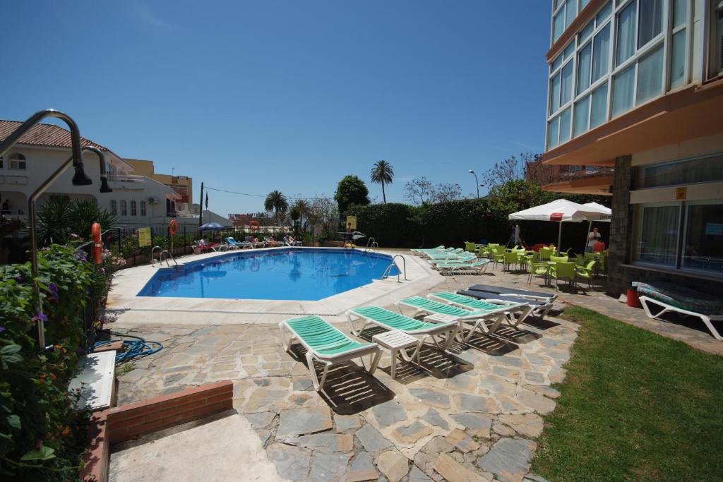 a swimming pool with lounge chairs next to a building at Apartamentos Doramar in Benalmádena