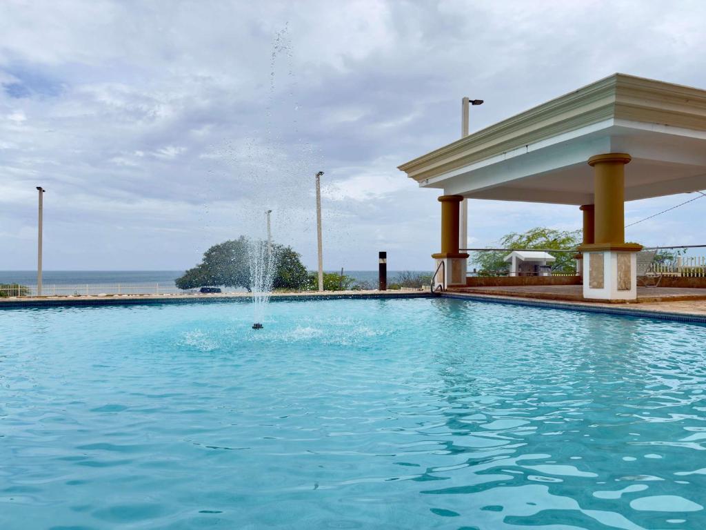 a swimming pool with a fountain in the middle at Oceanview Costa del Mar Condo with Pool and Smart TV in Pole Ojea